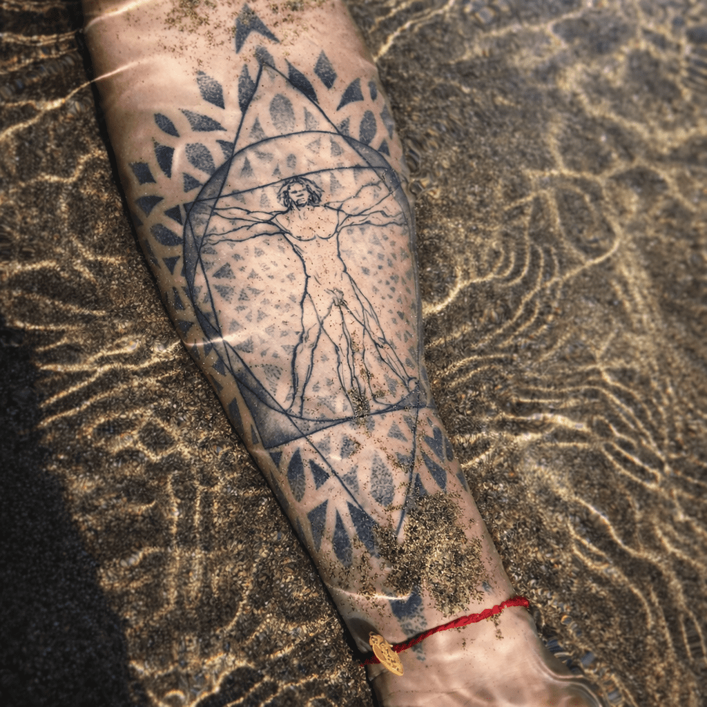 Antebrazo tatuado en puntillismo y línea fina, inspirado en Vitruvio, creado por GuaciMara en Tinta Canaria tattoo Studio
